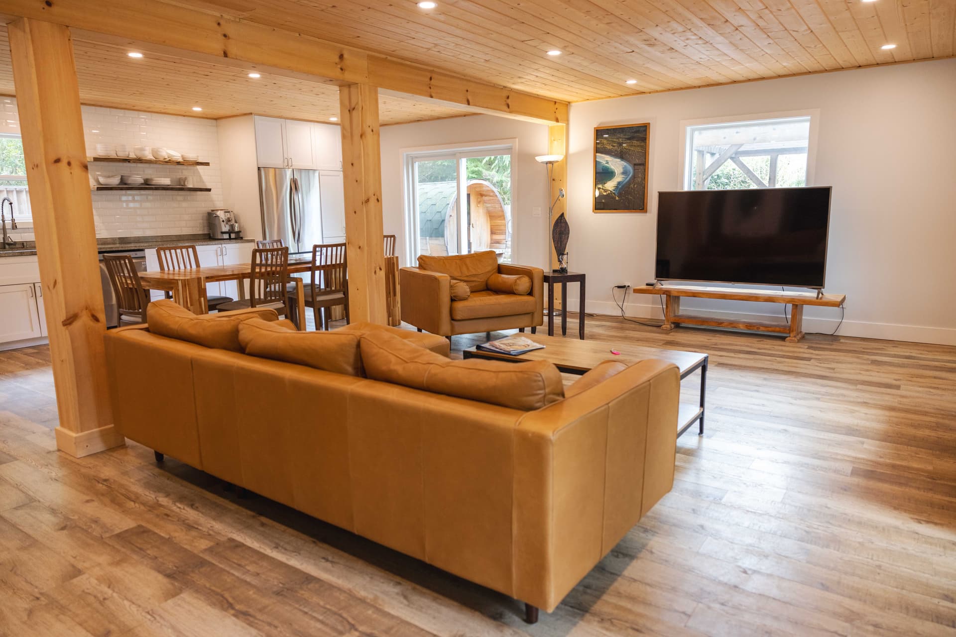 Open-plan living room with leather sofas and vaulted cedar ceiling