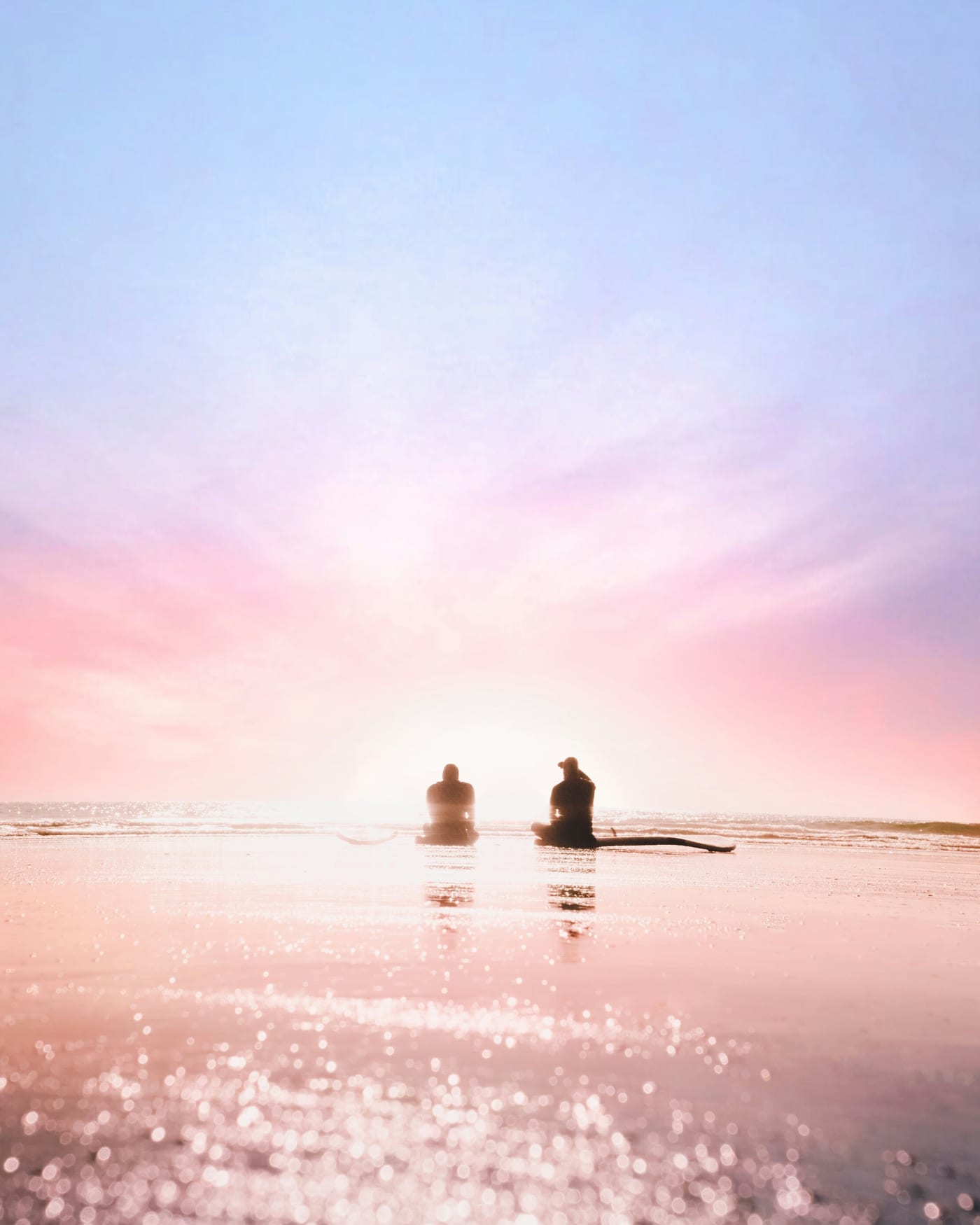 Silhouette of two people on Chesterman Beach at dawn, Tofino BC