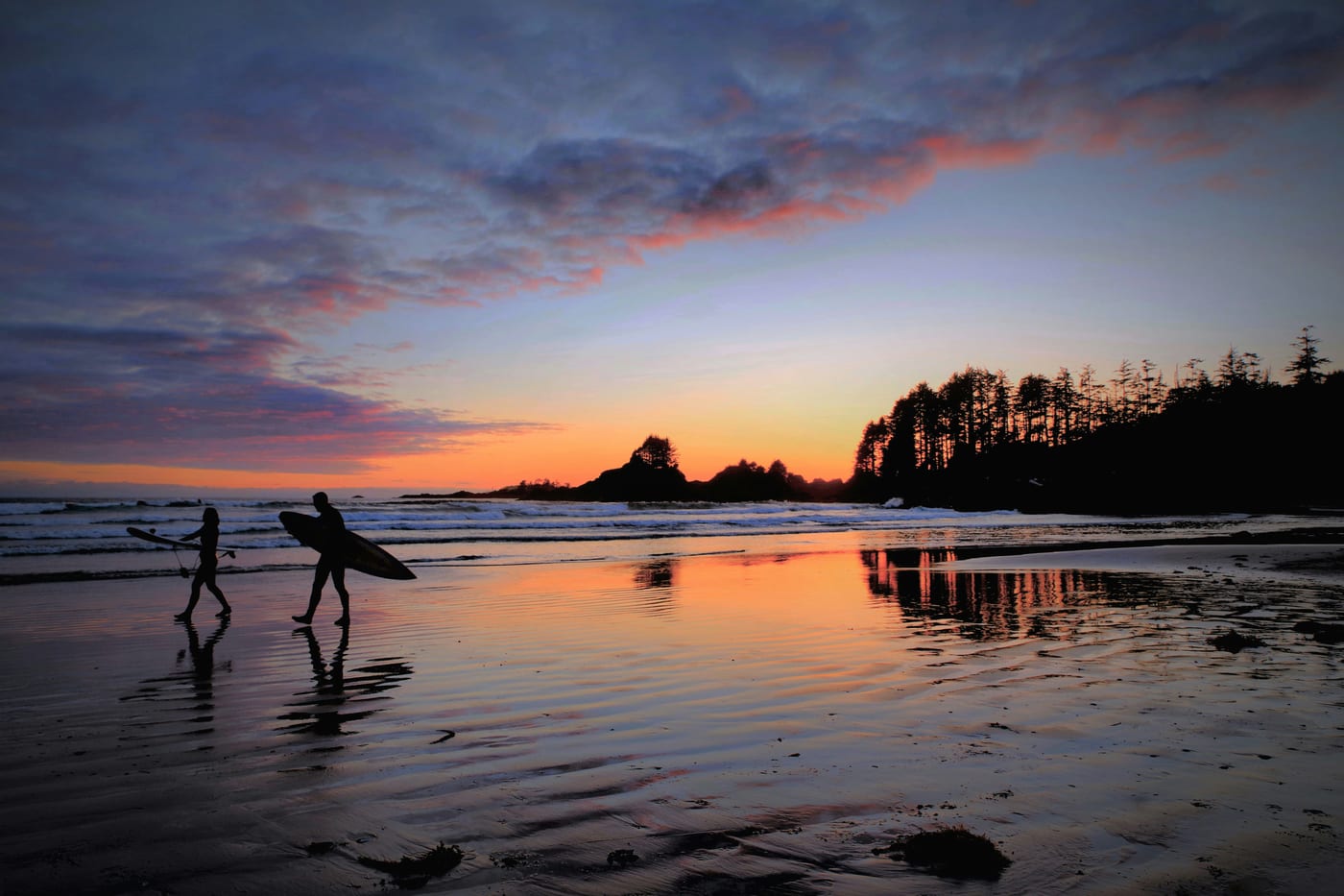 Surfer carrying board on a Tofino beach in fall