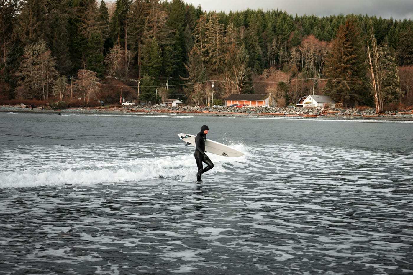 Surfer in full wetsuit holding surfboard ready for cold Pacific water